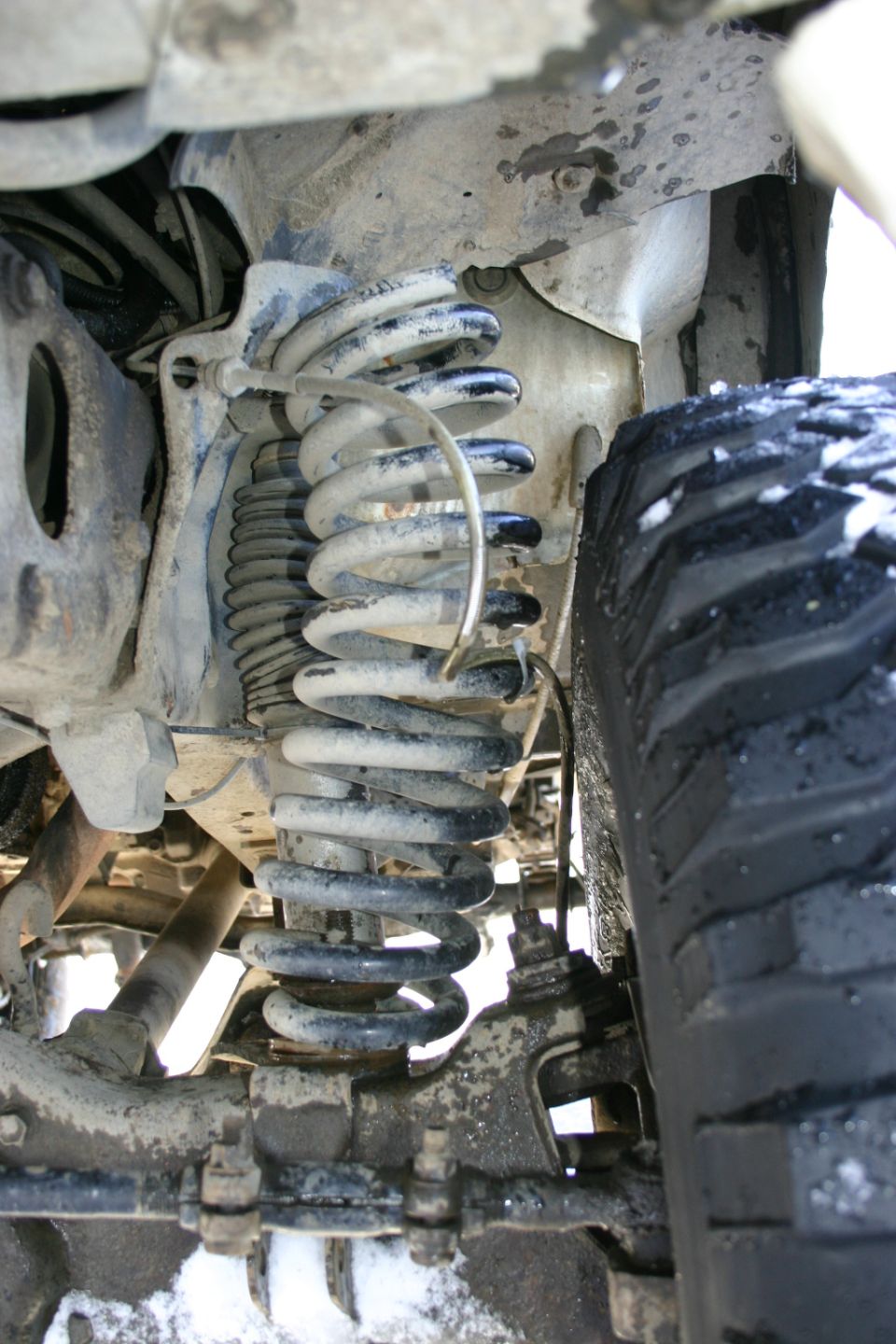 Close-up of a vehicle's front suspension with coil springs and a tire