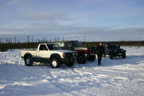 2003 Jeep TJ - Several off-road vehicles are parked in a snowy, treeless landscape under a partly cloudy sky.