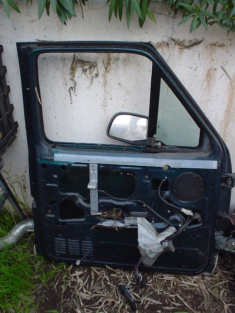 1993 Ford Bronco - A detached car door is shown outdoors, leaning against a wall with foliage above.