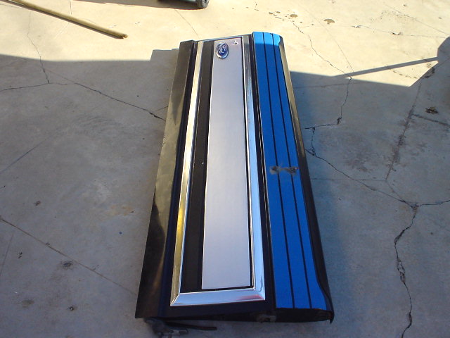 Tailgate with blue stripes and a silver panel, sitting on concrete