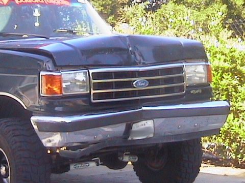1991 Ford Bronco - The front of a Ford truck shows significant damage to the hood and bumper area. A '4x4' badge is visible.