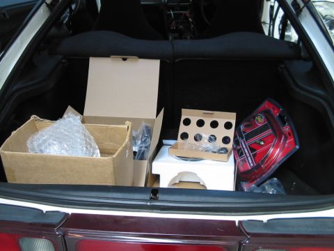 1994 Ford Probe - The trunk of a car is filled with various boxes and car parts, including items in red packaging.