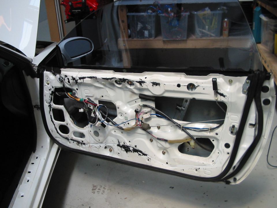 White car door interior with exposed wiring and components, viewed from the side