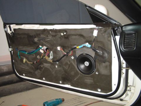 1994 Ford Probe - The interior of a car door is shown with the speaker and wiring exposed, indicating a repair or upgrade is in progress.
