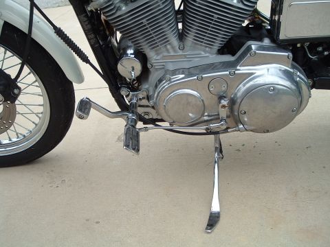 1995 Mercury Grand Marquis - Close-up view of a motorcycle's engine, front wheel, and kickstand on a concrete surface.