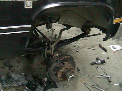 1981 Chevrolet C/K Pickup - The front suspension of a 1981 Chevrolet C/K Pickup is disassembled, with tools laid out on the garage floor.
