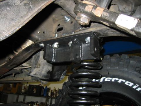 1992 Ford Bronco - Aftermarket suspension bracket and coil spring installation on a vehicle's undercarriage.