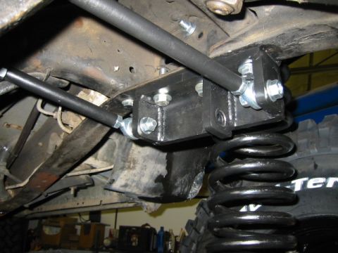 1992 Ford Bronco - Close-up view of aftermarket suspension modifications, including a heavy-duty bracket and coil spring.