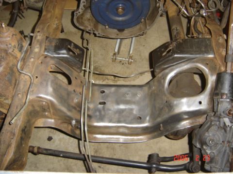 1990 Ford Bronco - Close overhead shot of a bare, stripped-to-metal engine crossmember and inner fender area with all grease and coating removed, ready for pa…