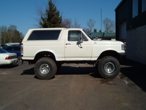 1989 Ford Bronco - Side view of a lifted 1989 Ford Bronco with large off-road tires.