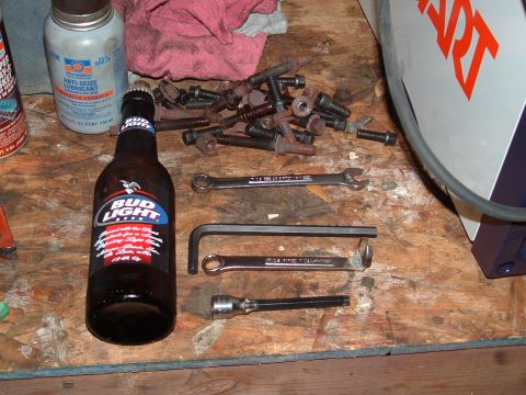 1989 Ford Bronco - A collection of wrenches, an Allen key, a socket extension, and a bottle of Bud Light are laid out on a wooden workbench.