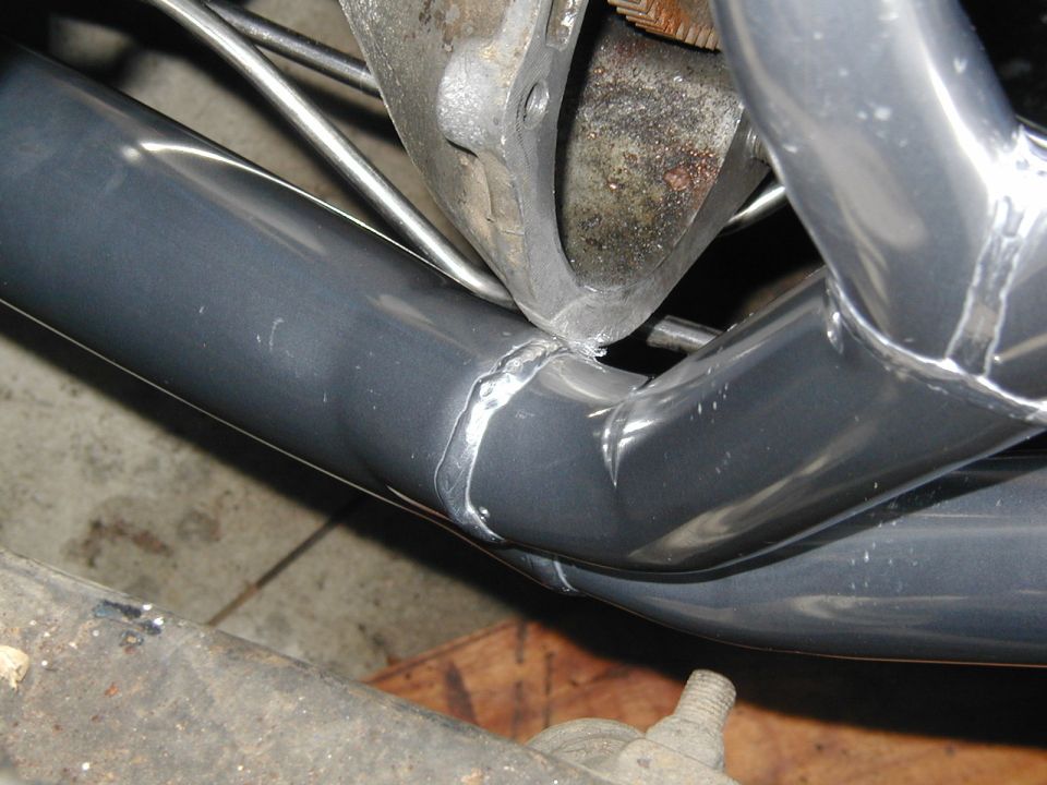Gray exhaust headers with visible welds, attached to engine block