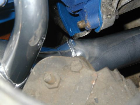 1968 Ford Mustang - A close-up view of exhaust headers and a blue engine mount, with visible bolts and metalwork.