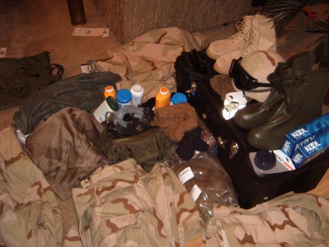 1988 Ford Bronco - A collection of military gear, including camouflage clothing, boots, and personal items, is spread out on the floor.