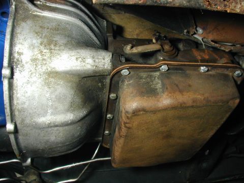 1968 Ford Mustang - Underside view of a transmission oil pan and bell housing, with visible bolts and signs of wear.