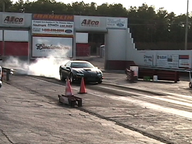 Black Chevrolet Camaro doing a burnout at a drag strip