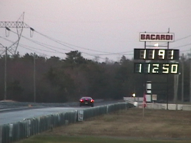 Red sports car at drag strip with 11.91 and 112.50 on scoreboard