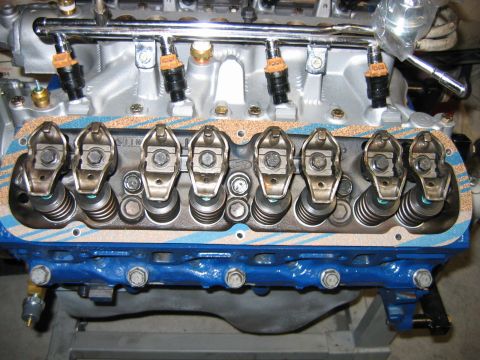 1992 Ford Bronco - Close-up of a freshly rebuilt V8 cylinder head with exposed rocker arms and valve springs, topped by an aluminum intake with a fuel rail an…
