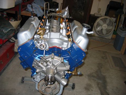 1992 Ford Bronco - A freshly rebuilt Ford V8 engine block, painted Ford blue with polished aluminum valve covers, timing cover, and water pump, sitting on an…