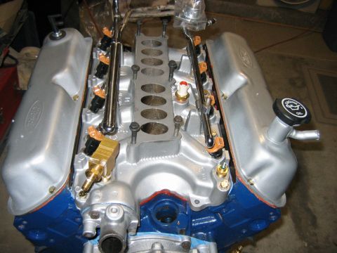 1992 Ford Bronco - Top-down view of a freshly rebuilt Ford V8 engine with silver-painted valve covers bearing the Ford oval logo, an intake valley showing the…