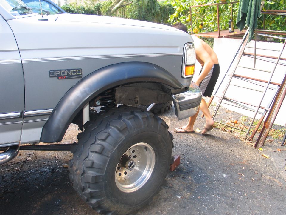Lifted two-tone Ford Bronco XLT front fender with huge off-road tire on a polished wheel