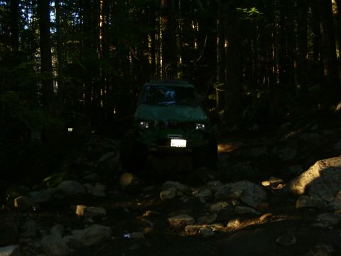 1990 Ford Bronco - Green 1990 Ford Bronco navigating a challenging off-road path through a forest.