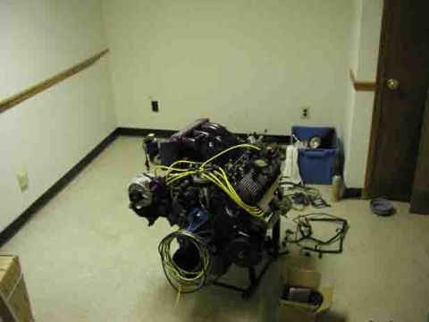 1988 Ford Bronco - Engine assembly on a stand, with wiring harness on the floor.