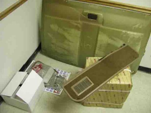 1988 Ford Bronco - A car door panel and various car parts are laid out on the floor next to boxes.