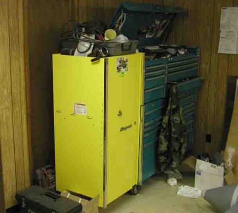 1988 Ford Bronco - A yellow Snap-on side locker cabinet stands beside a green multi-drawer roll-away tool chest in a wood-paneled garage corner, with hoses, s…