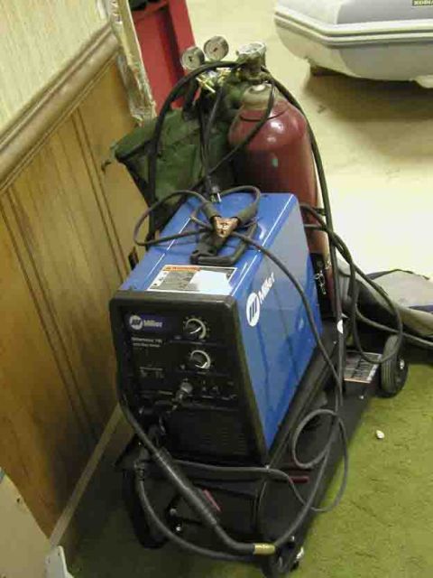 1988 Ford Bronco - A blue Miller welding machine is connected to gas cylinders and sits on a cart, ready for use.