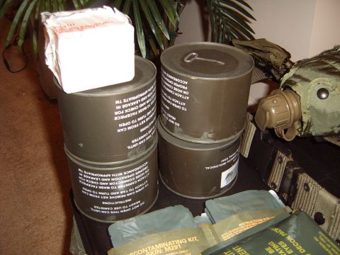 1988 Ford Bronco - Military canisters and decontamination kits are arranged on a surface, with a canteen visible on the right side.