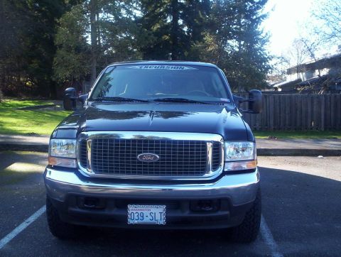 2004 Ford Excursion - This Ford Excursion is parked in a lot with trees and a building in the background.