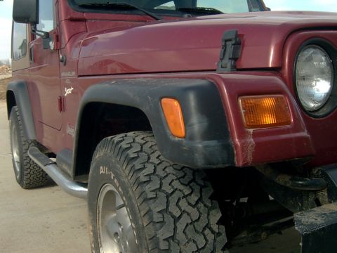 1998 Jeep TJ - Close-up of a 1998 Jeep TJ's front fender and tire, showing the "WRANGLER" and "Sport" badging.