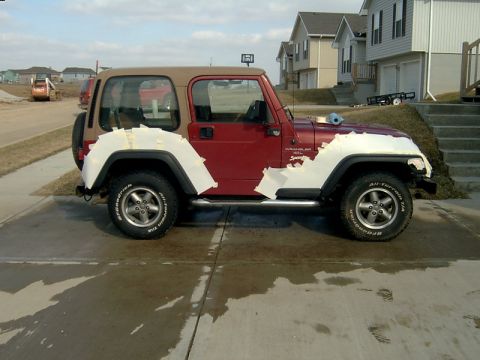 1998 Jeep TJ - A red 1998 Jeep TJ is parked on a driveway with its fenders taped off, possibly for painting.