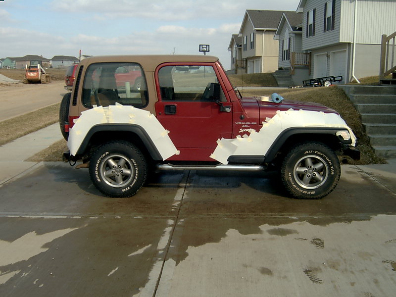 Red 1998 Jeep TJ side view with tape on fenders
