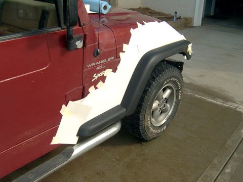 1998 Jeep TJ - A red Jeep Wrangler is being prepped for work on its front fender, with protective coverings applied.