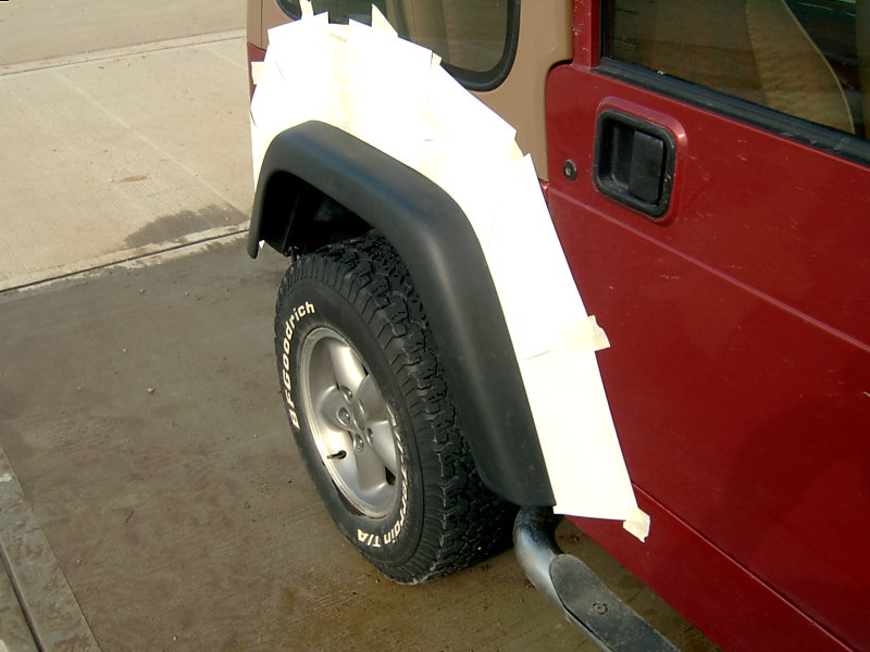 Red Jeep side view, masking tape covers the rear fender and part of the door