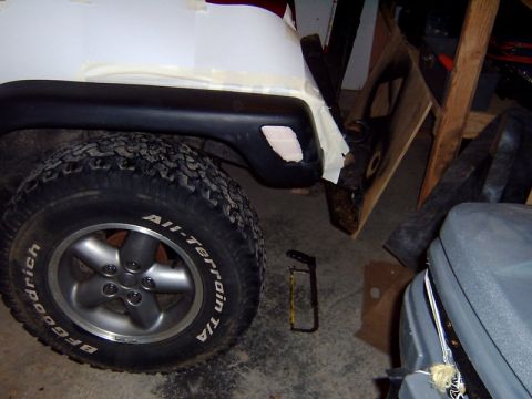 1998 Jeep TJ - Close-up of a Jeep TJ fender flare and tire, with some bodywork in progress.