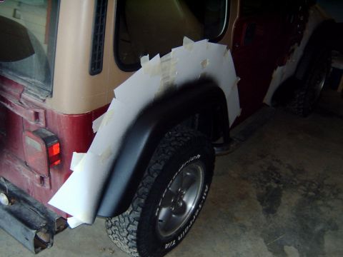1998 Jeep TJ - A paper template is taped to the rear fender of a Jeep, likely for modification or repair.