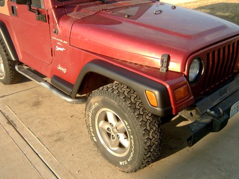 1998 Jeep TJ - A red Jeep Wrangler is shown from the front 3/4 angle, highlighting its tires and side steps.