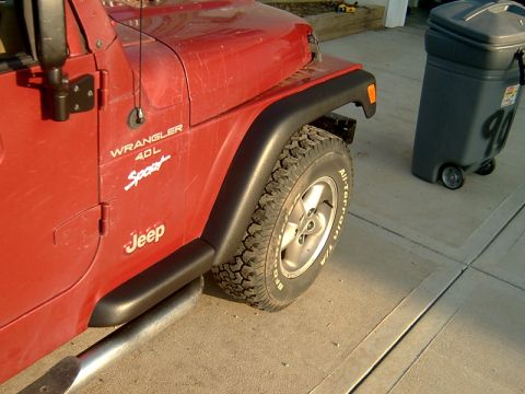 1998 Jeep TJ - Side view of a red 1998 Jeep TJ Wrangler 4.0L Sport, showing its side steps and fender flares.