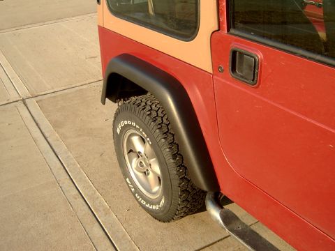 1998 Jeep TJ - Red Jeep Wrangler with tan top, showing the side profile and tire details.