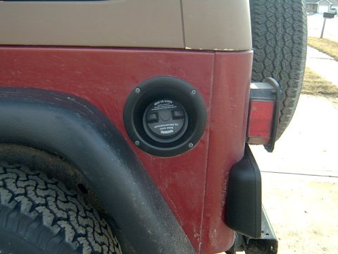 1998 Jeep TJ - Close-up of a red Jeep TJ's rear quarter panel, showing the fuel door and spare tire.