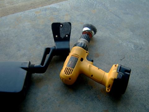 1998 Jeep TJ - A black mirror assembly and a yellow power drill with a wire brush attachment are shown on a concrete surface.