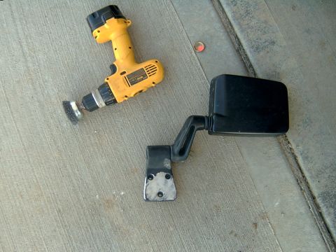 1998 Jeep TJ - A black Jeep TJ side mirror assembly is shown next to a yellow drill with a wire brush attachment.