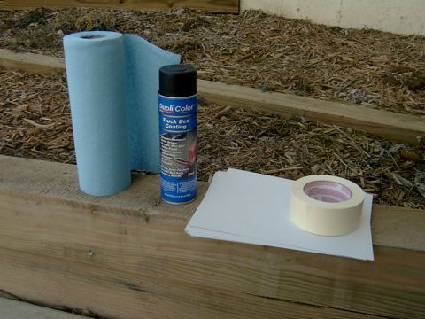 1998 Jeep TJ - Supplies for applying truck bed coating: shop towels, spray can, paper, and masking tape.