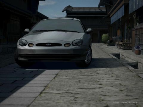 2001 Ford Taurus - A silver sedan, likely a 2000 Ford Taurus, is parked on a cobblestone street in front of buildings.