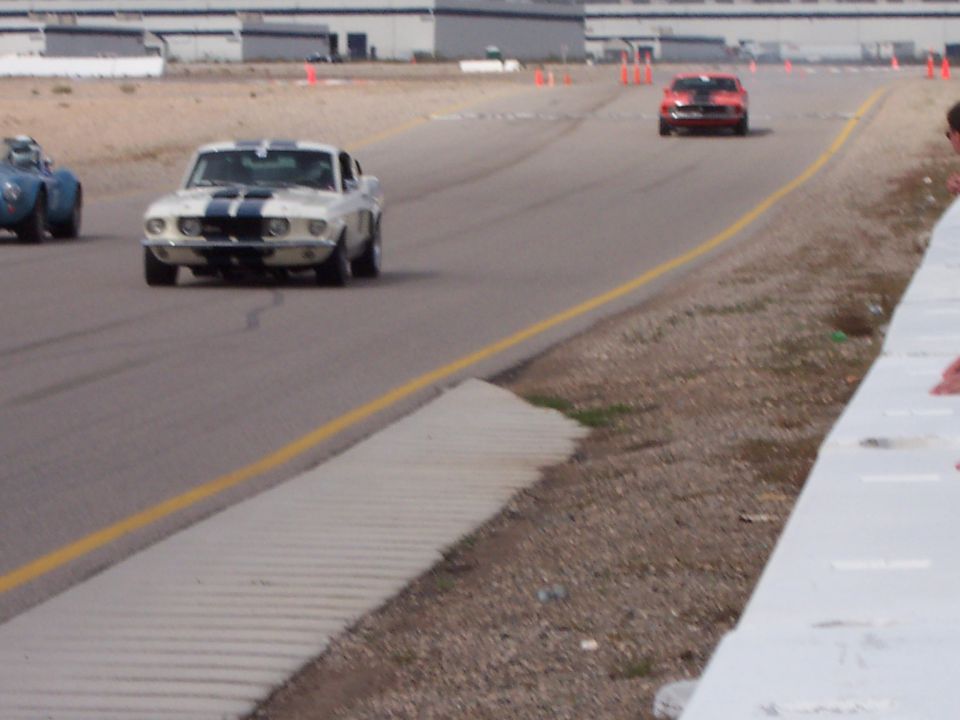 White 1969 muscle car with blue stripes on track