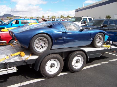 1971 Ford Mustang - Blue race car being transported on a trailer, with other vehicles in the background.