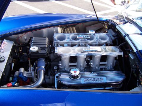 1971 Ford Mustang - The engine bay of a blue Shelby Cobra features a powerful V8 engine with prominent "427" markings.
